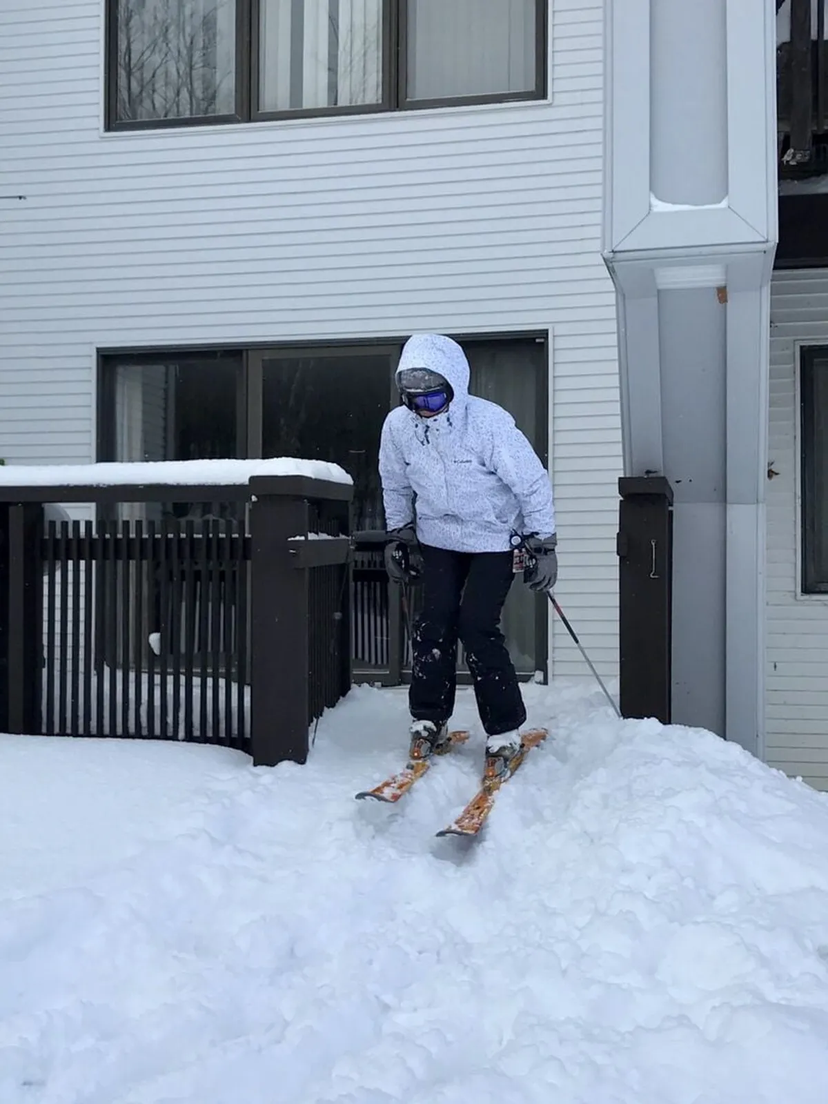 A skier in action on a snow-covered slope just outside the building, with the structure itself visible in the winter landscape. The scene is lively and captures the thrill of ski-in/ski-out convenience directly from the property.