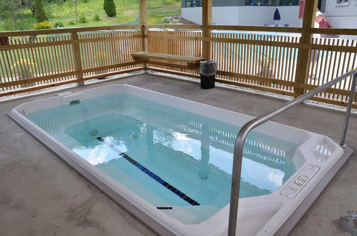 A cozy, wood-enclosed hot tub area complete with benches and privacy fencing. The tub steams invitingly, promising a soothing soak after a day of mountain adventures. The setting feels private and tranquil, perfect for unwinding.